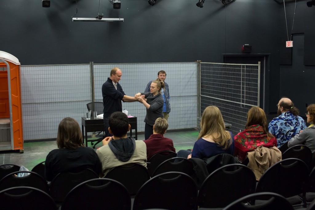 Praxis Artistic Producer Aislinn Rose demonstrates how to be safely zip-tied while writer performer Tommy Taylor looks on.