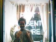 Camila standing infront of neon sign in window that says 'past, present, future'.