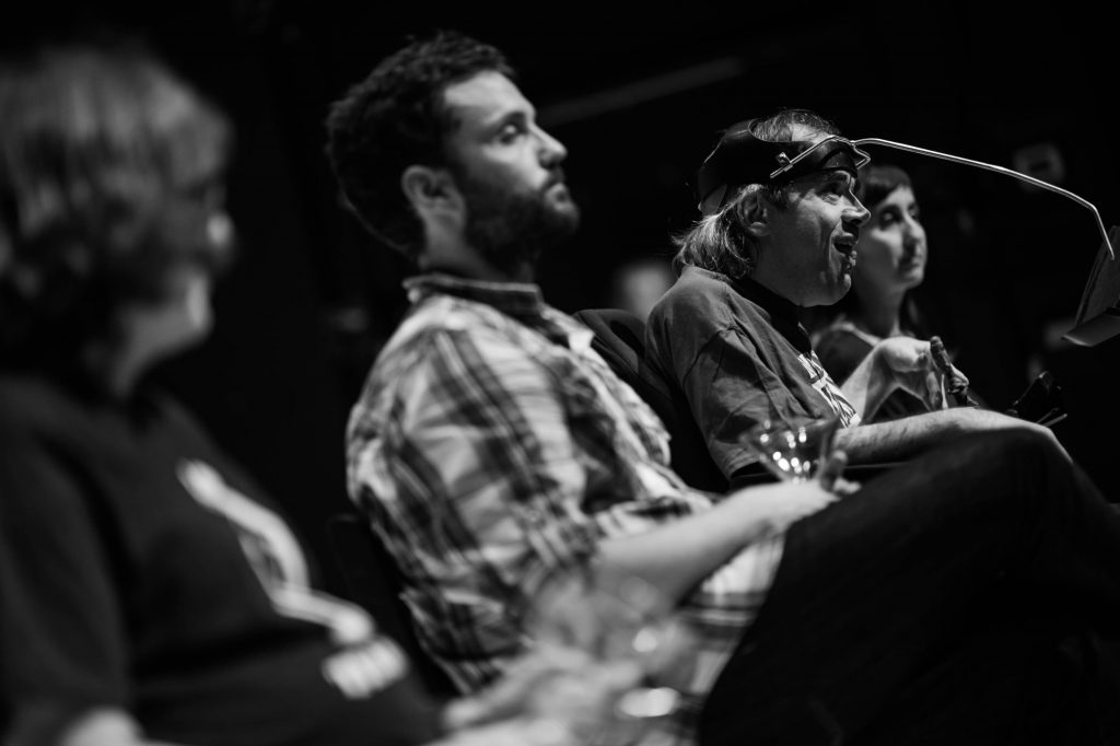 4 seated performers, with different visible abilities, facing out to audience.