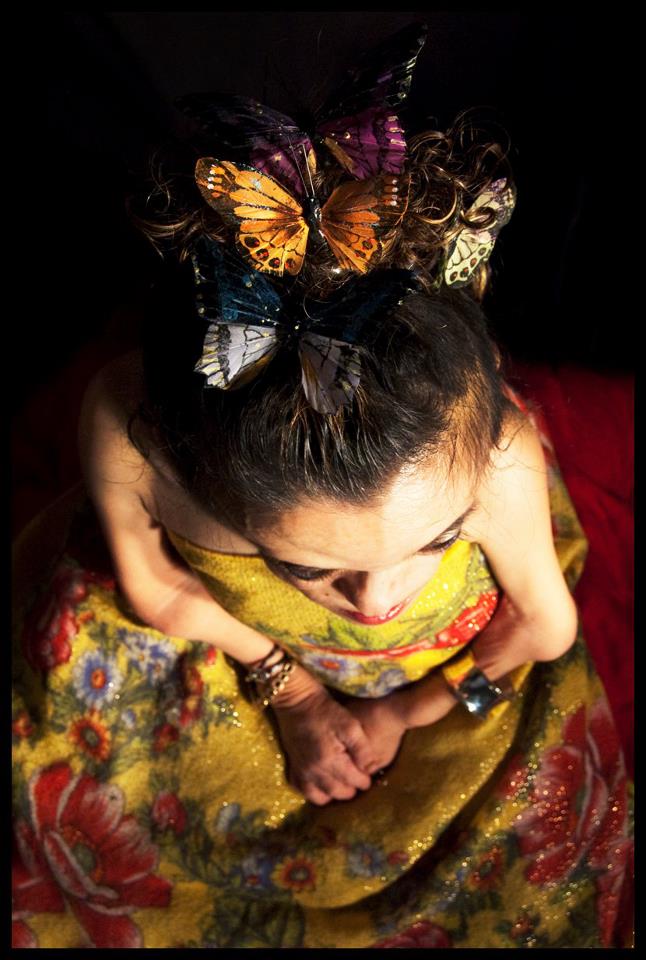 Camera hovers over Elaine's head. Her hair is held up by life-life butterflies and she's wearing a flowing yellow dress with flowers.