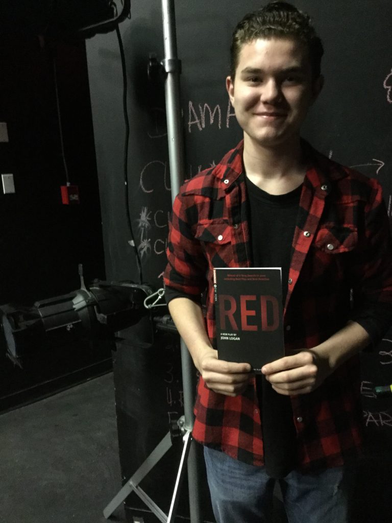 Trent, high school boy, holding a copy of the script for Red by John Logan. 